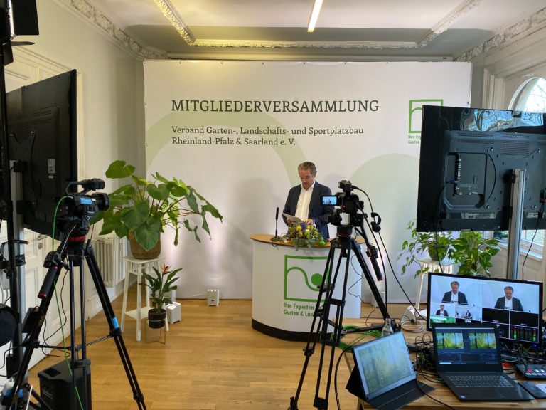 Hybride Mitgliederversammlung des Verbands Garten-, Landschafts- und Sportplatzbau Rheinland-Pfalz & Saarland: Redner am Pult, davor Kameras, Monitore und Regietechnik